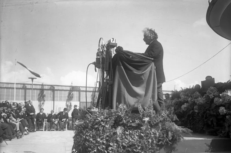 Albert Einstein enthüllt ein Gerät bei der Eröffnung der Funkausstellung Berlin 1930, vor sitzendem Publikum.